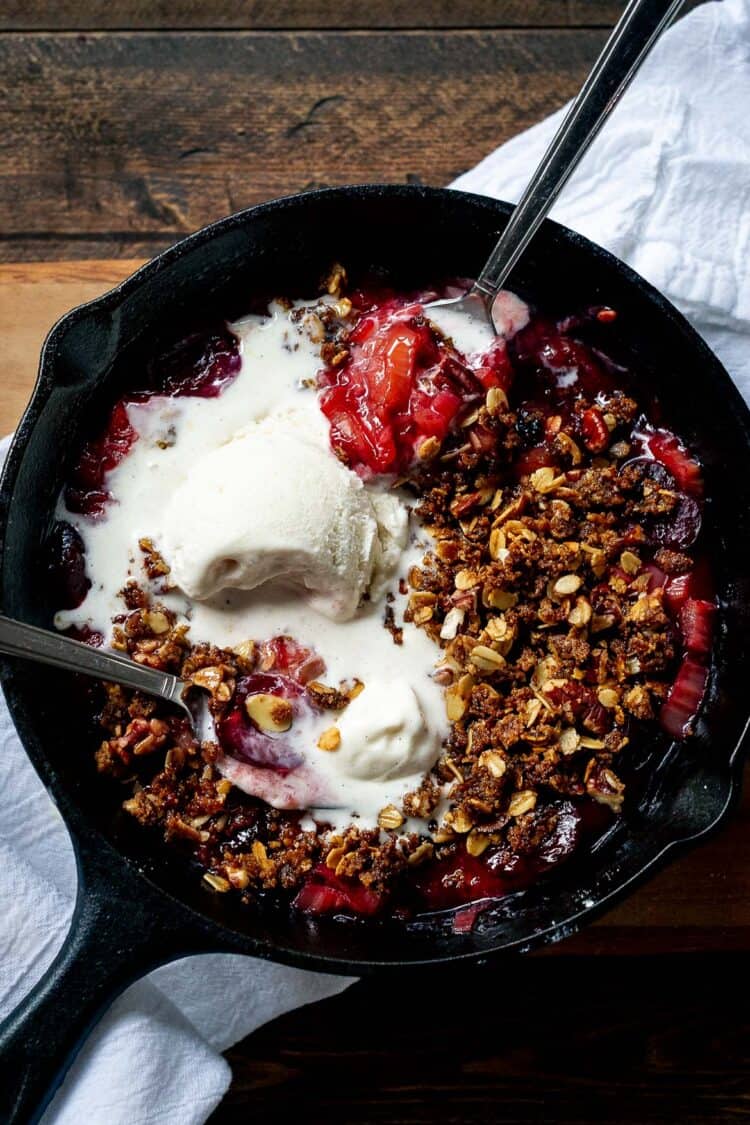 Stovetop Rhubarb-Cherry Crisp with ice cream in a skillet.