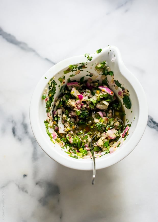 A white dish filled with a bright chimichurri sauce.