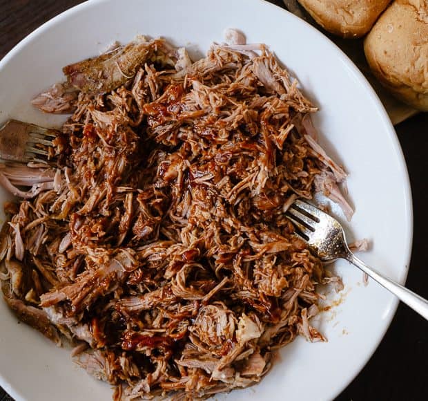 Slow Cooker Stout Pulled Pork shredded on a white serving plate.