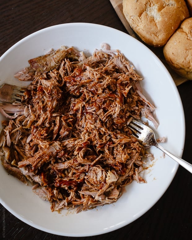 Slow Cooker Stout Pulled Pork shredded on a white serving plate.