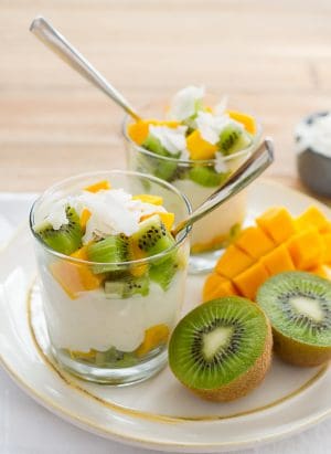 Tropical rice pudding layered in glasses with coconut flakes, chopped kiwi, and chopped mango.