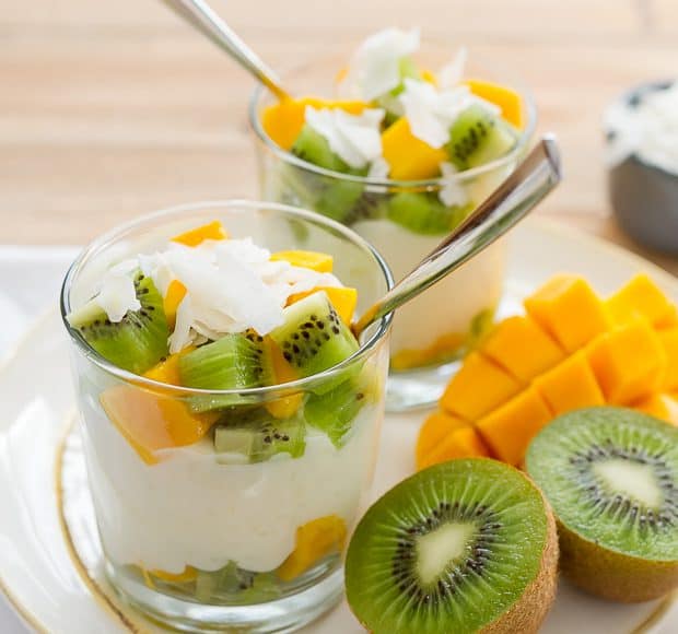 Rice pudding layered in glasses with coconut flakes, chopped kiwi and chopped mango