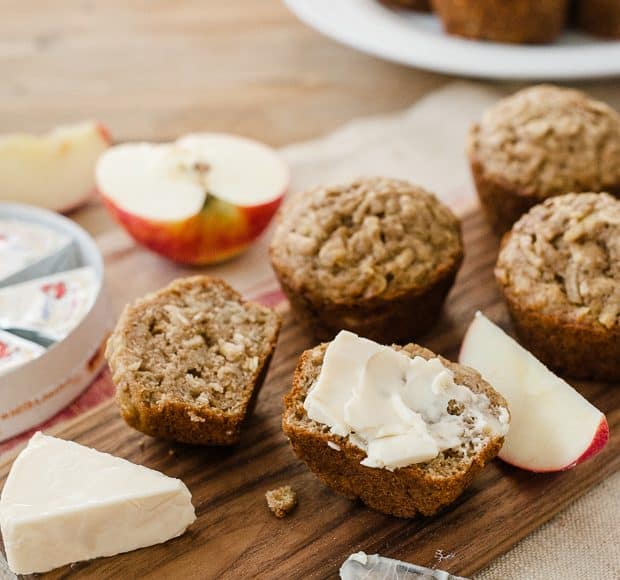 Muffins halved and spread with a creamy cheese on a wooden serving board.