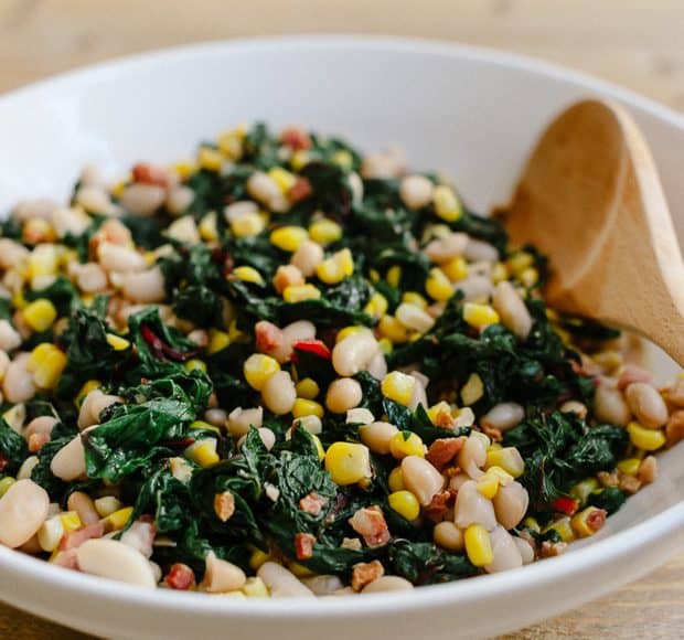 A white bowl filled with Swiss Chard with Pancetta, Corn and Cannelini Beans.