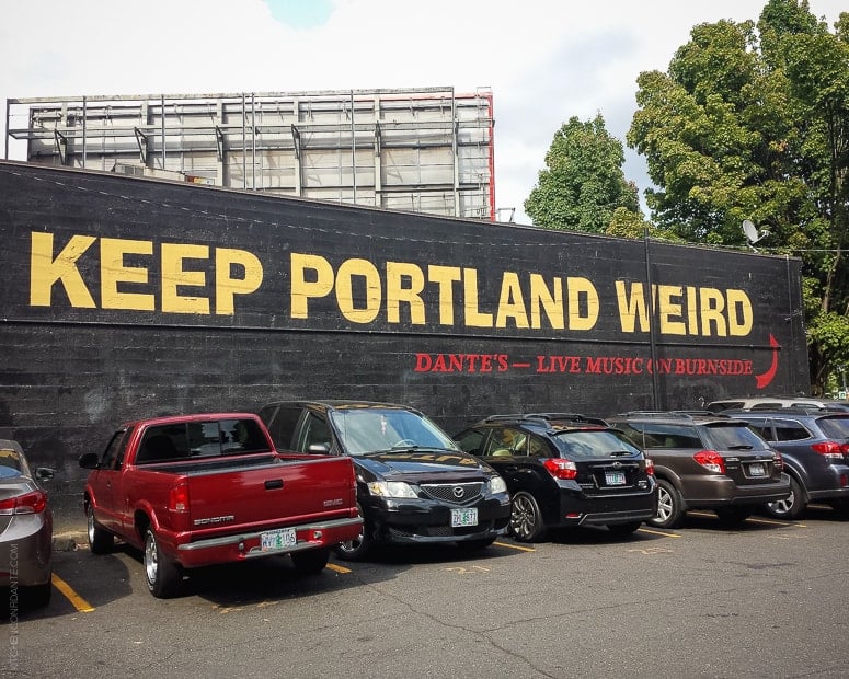 Keep Portland Weird mural painted on the side of building by parking lot.
