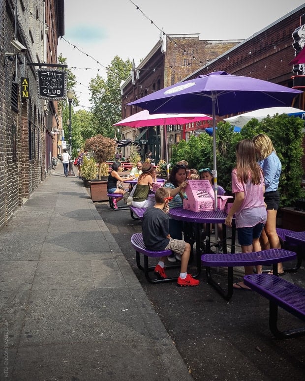People gathered around purple picnic tables eating VooDoo Doughnuts