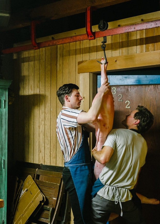 Two men hanging a butchered animal at an Advanced Butchery Class