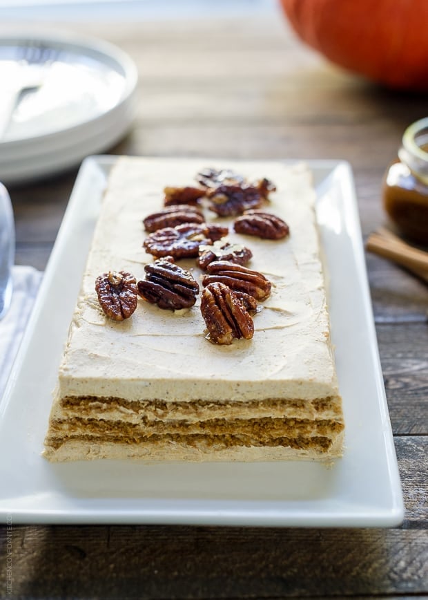 No Bake Pumpkin Spice Kahlúa Cheesecake served a on a white rectangular platter with candied pecans on top.