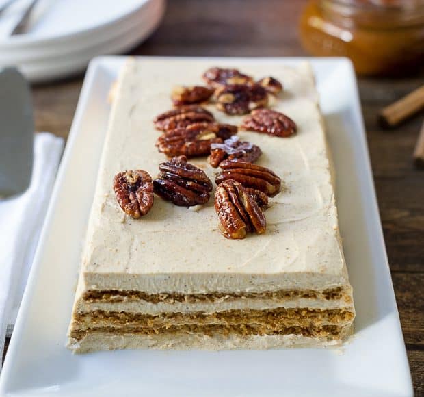 A No Bake Pumpkin Spice Kahlúa Cheesecake served a on a white rectangular platter with candied pecans on top.