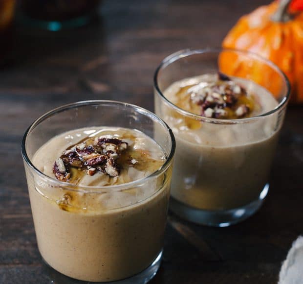 Two glasses filled with Pumpkin Butter Smoothie and topped with a drizzle of honey and candied pecans.