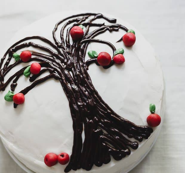 A Sweet Potato Apple Cake decorated with white icing and an apple tree design.