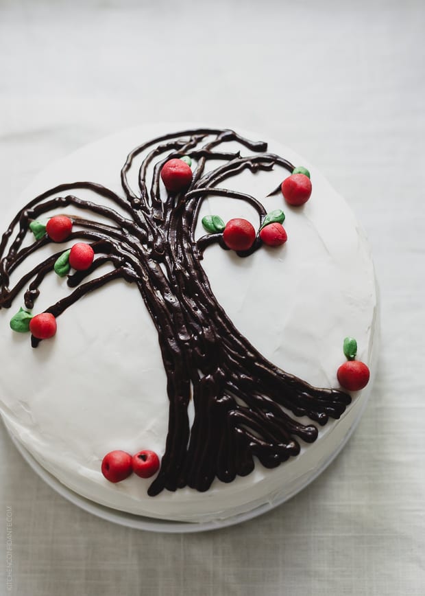 A Sweet Potato Apple Cake decorated with white icing and an apple tree design.