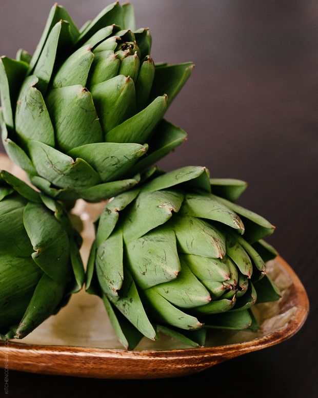 Three artichokes in a decorative dish.