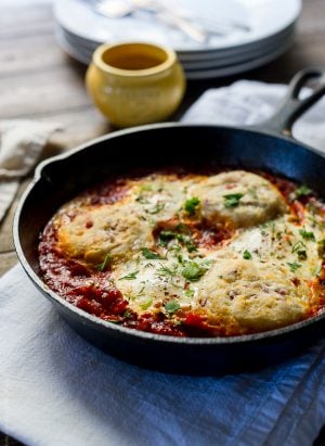 Cast iron skillet filled with Baked Eggs with Cheesy Pancetta Biscuits.