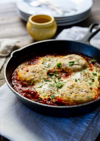 Cast iron skillet filled with Baked Eggs with Cheesy Pancetta Biscuits.