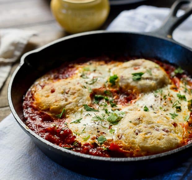 Cast iron skillet filled with Baked Eggs with Cheesy Pancetta Biscuits.