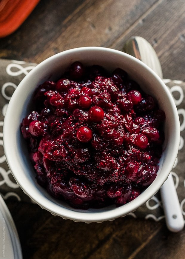 A bowl of cranberry sauce on a wooden surface.