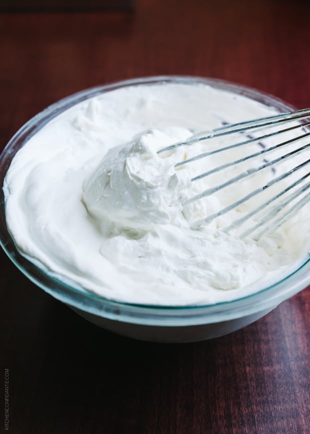 Whipping heavy cream with a whisk in a glass bowl.
