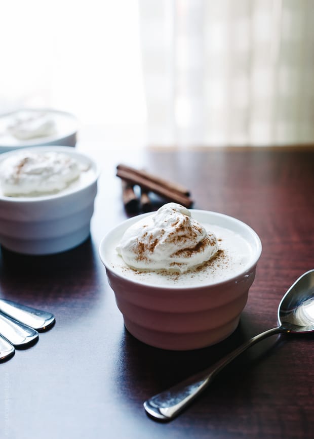 A cup of eggnog mousse topped with whipped cream and cinnamon sprinkles.