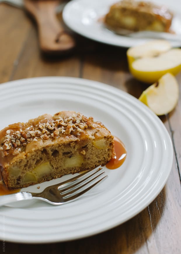 A slice of apple cake on a white plate with a fork.