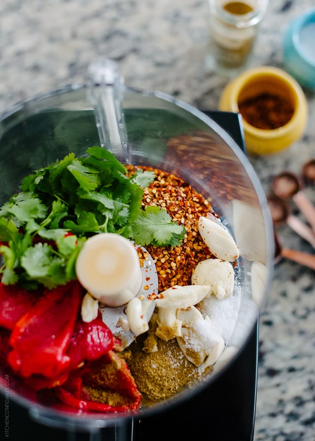 Ingredients for harissa (including roasted red peppers and cilantro) in a food processor.