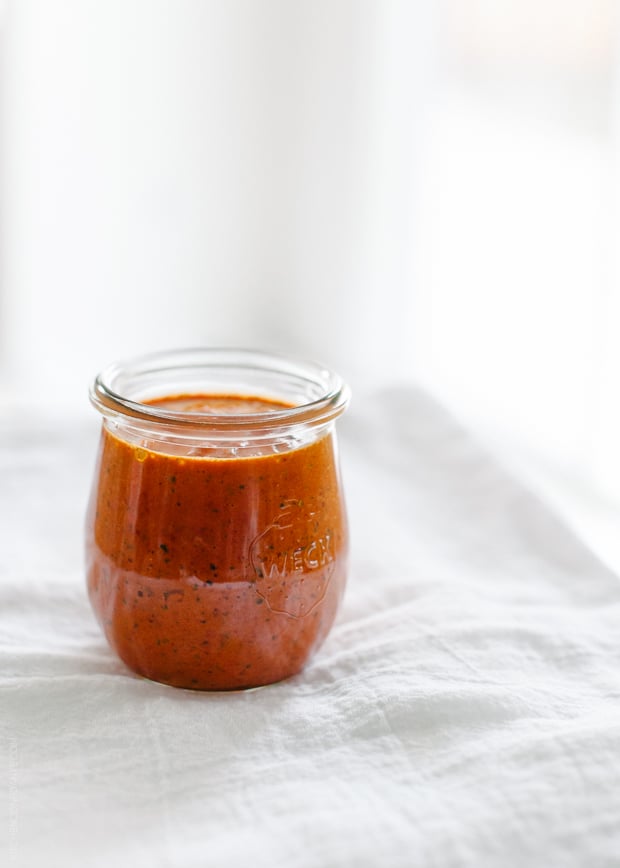 A jar of homemade harissa in front of a white background.