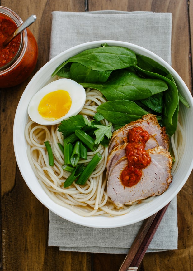 A bowl of ramen topped with pork slices, a soft egg and harissa.