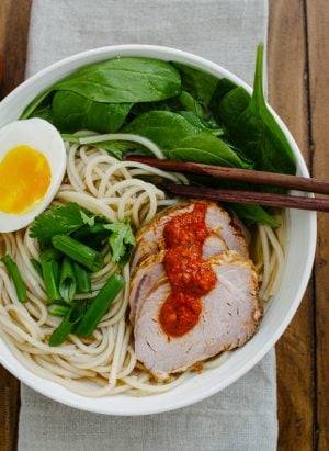 A bowl of ramen topped with pork slices, a soft egg and harissa.