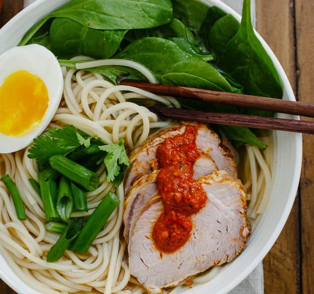 A bowl of ramen topped with pork slices, a soft egg and harissa.