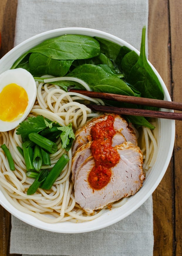 A bowl of ramen topped with pork slices, a soft egg and harissa.