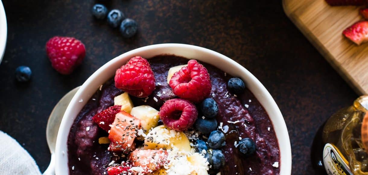 Acai Berry Bowl topped with bananas, granola, berries, coconut, chia seeds and honey.