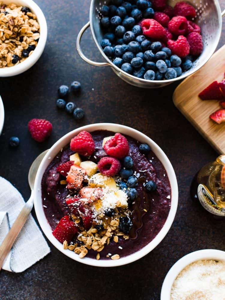 Acai Berry Bowl topped with bananas, granola, berries, coconut, chia seeds and honey.