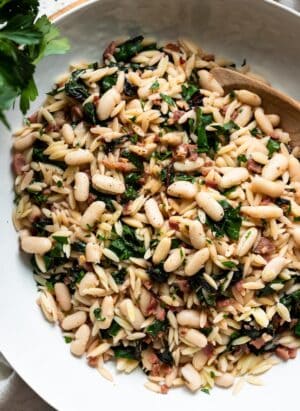 Swiss Chard with Orzo, Cannellini Beans and Pancetta in a white serving dish.