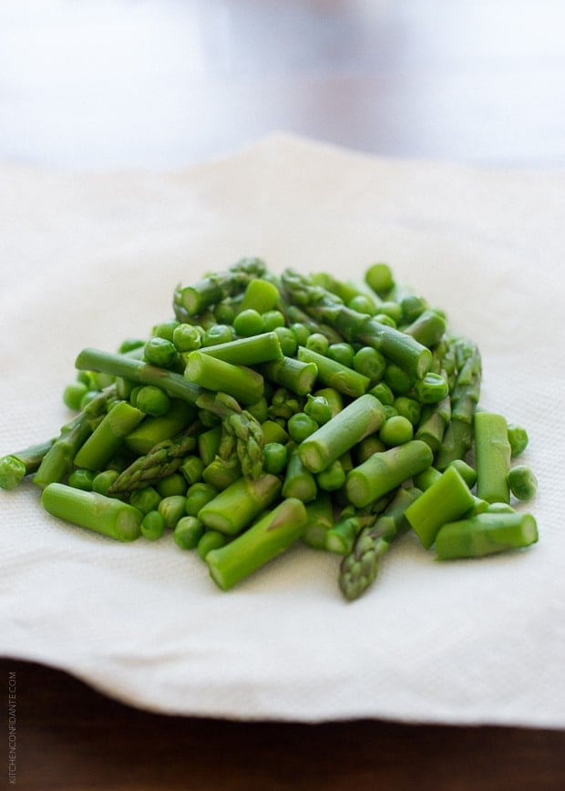 A small pile of fresh sweet peas and chopped asparagus.