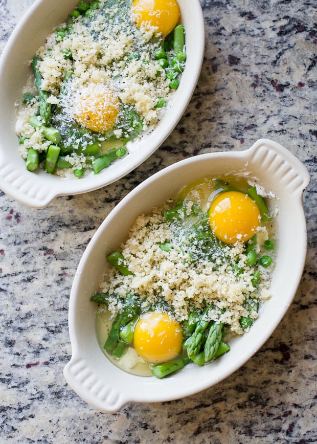 Ramekins filled with asparagus, peas, and eggs, ready to be baked.