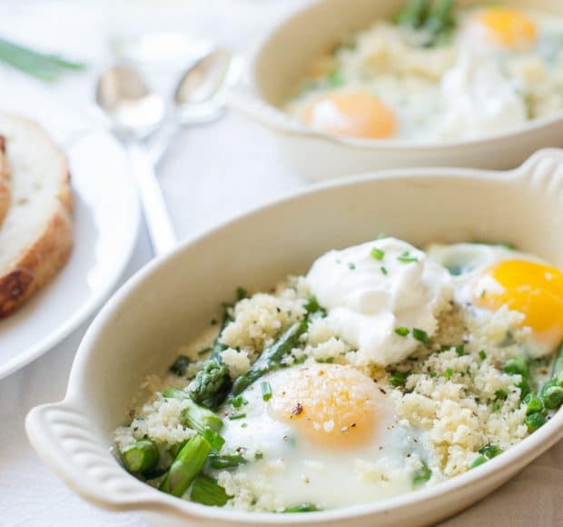 A small white ramekin filled with baked eggs, asparagus, and peas.