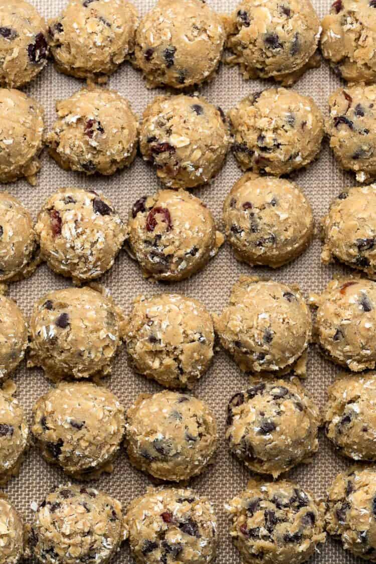 A white plate filled with Chocolate Chip Cranberry Oat Cookies alongside tall glasses of milk.