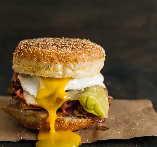 A Cubano Breakfast Sandwich made with an English Muffin and piled high with meat and a sunny side up egg.