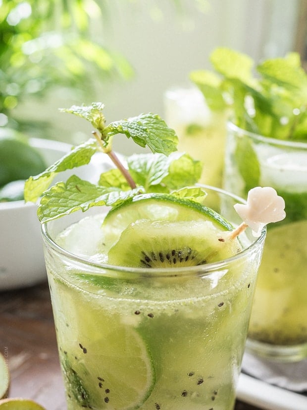 Kiwi Lime Mojitos topped with slices of lime, kiwi, and a sprig of mint.
