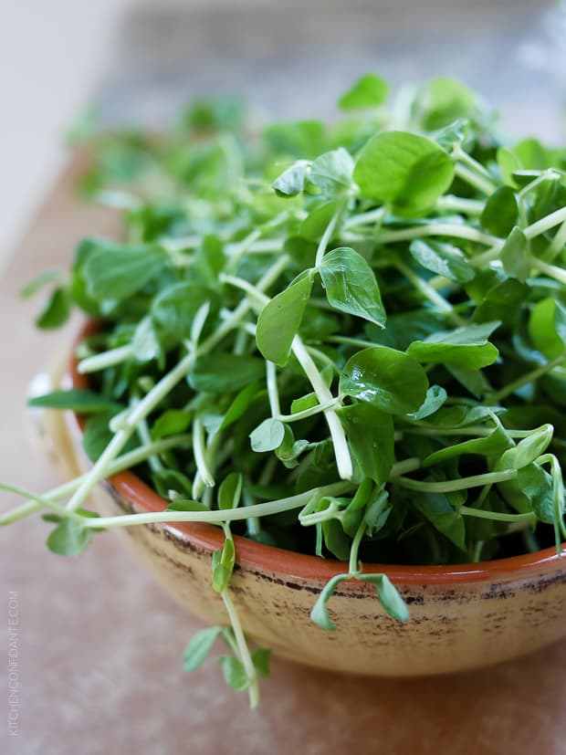 Delicate pea shoots in an earthenware bowl.