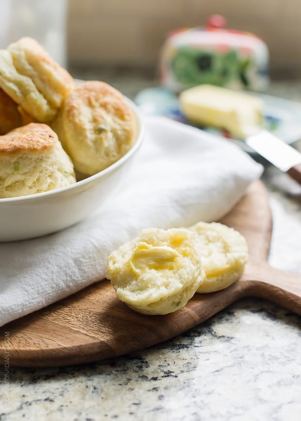 A biscuit broken in half and spread with butter.