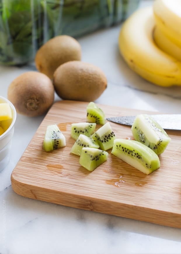 Chopped kiwi on a wooden cutting board for a Green Smoothie Bowl