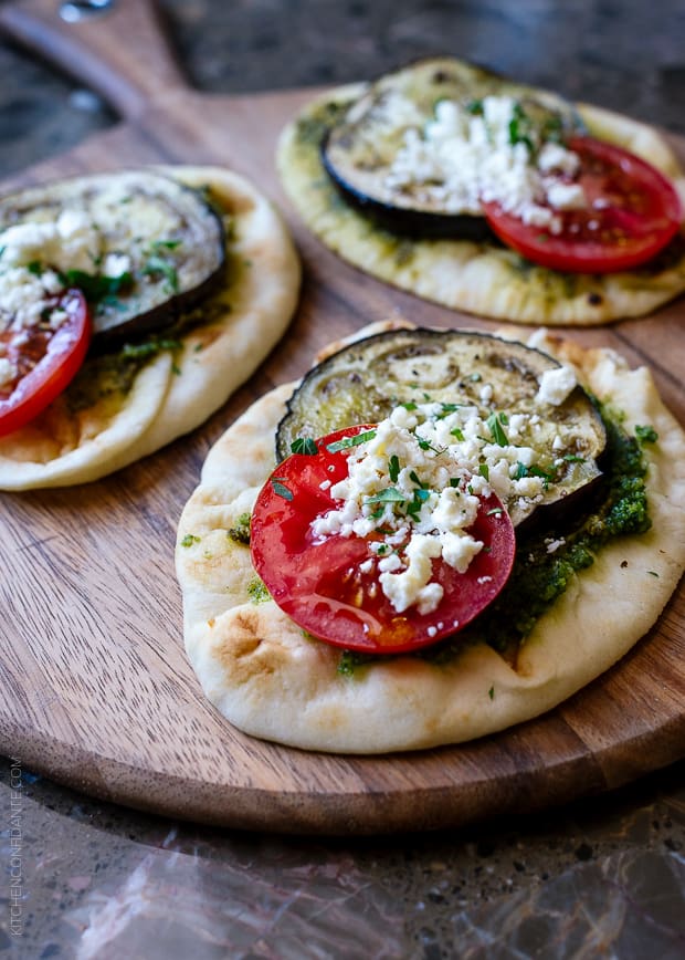 Mini naan topped with roasted vegetables on a wooden surface.