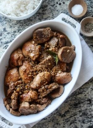 A white serving dish filled with Filipino Chicken and Pork Adobo.