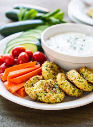 Baked Zucchini Fritters with Tzatziki on a white plate.