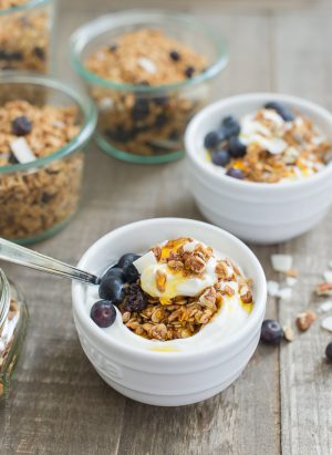 Blueberry Maple Granola served with yogurt and honey in a small white bowl.