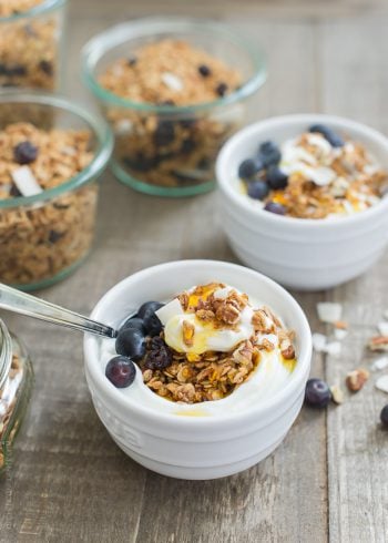 Blueberry Maple Granola served with yogurt and honey in a small white bowl.