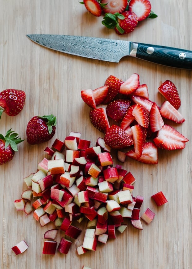 Chopped strawberries and rhubarb on a cutting board.