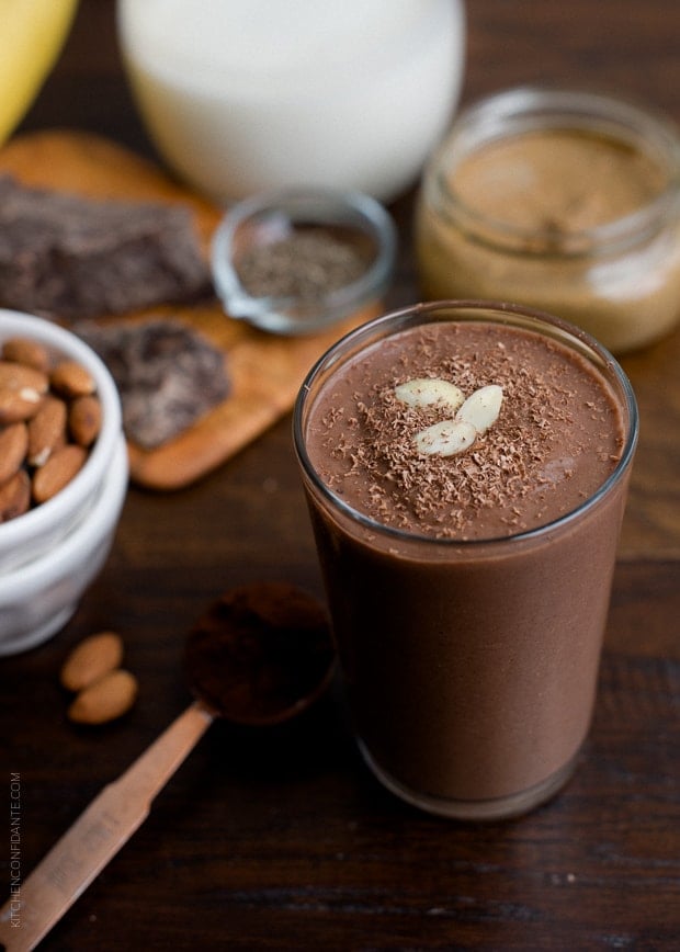A Dark Chocolate Almond Butter Smoothie in a glass on a wooden surface.