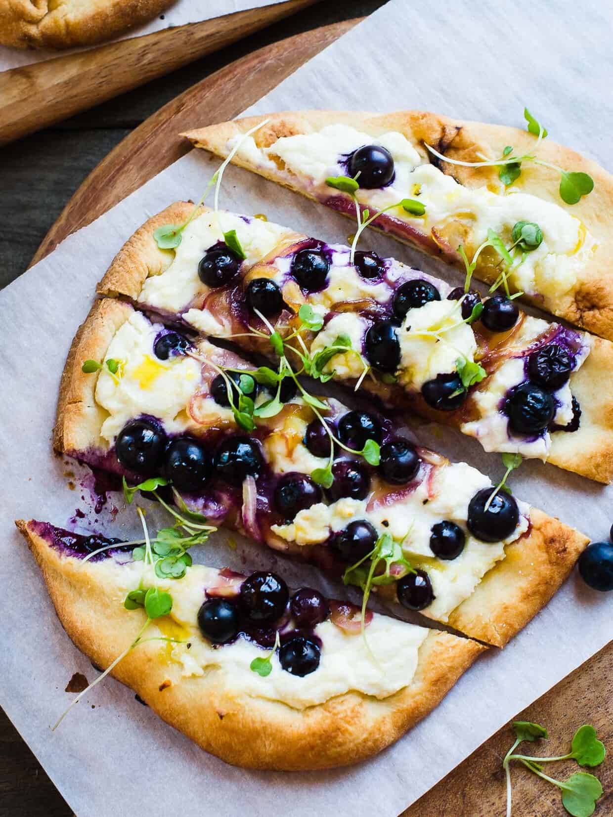 Blueberry, Feta and Honey-Caramelized Onion Naan Pizza on a cutting board.